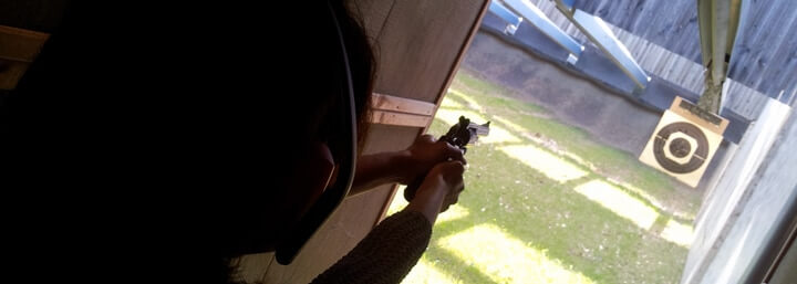 Eine Schützin beim Schießen lernen schießt mit einem Revolver am Schießstand auf eine Scheibe auf 10 Meter.